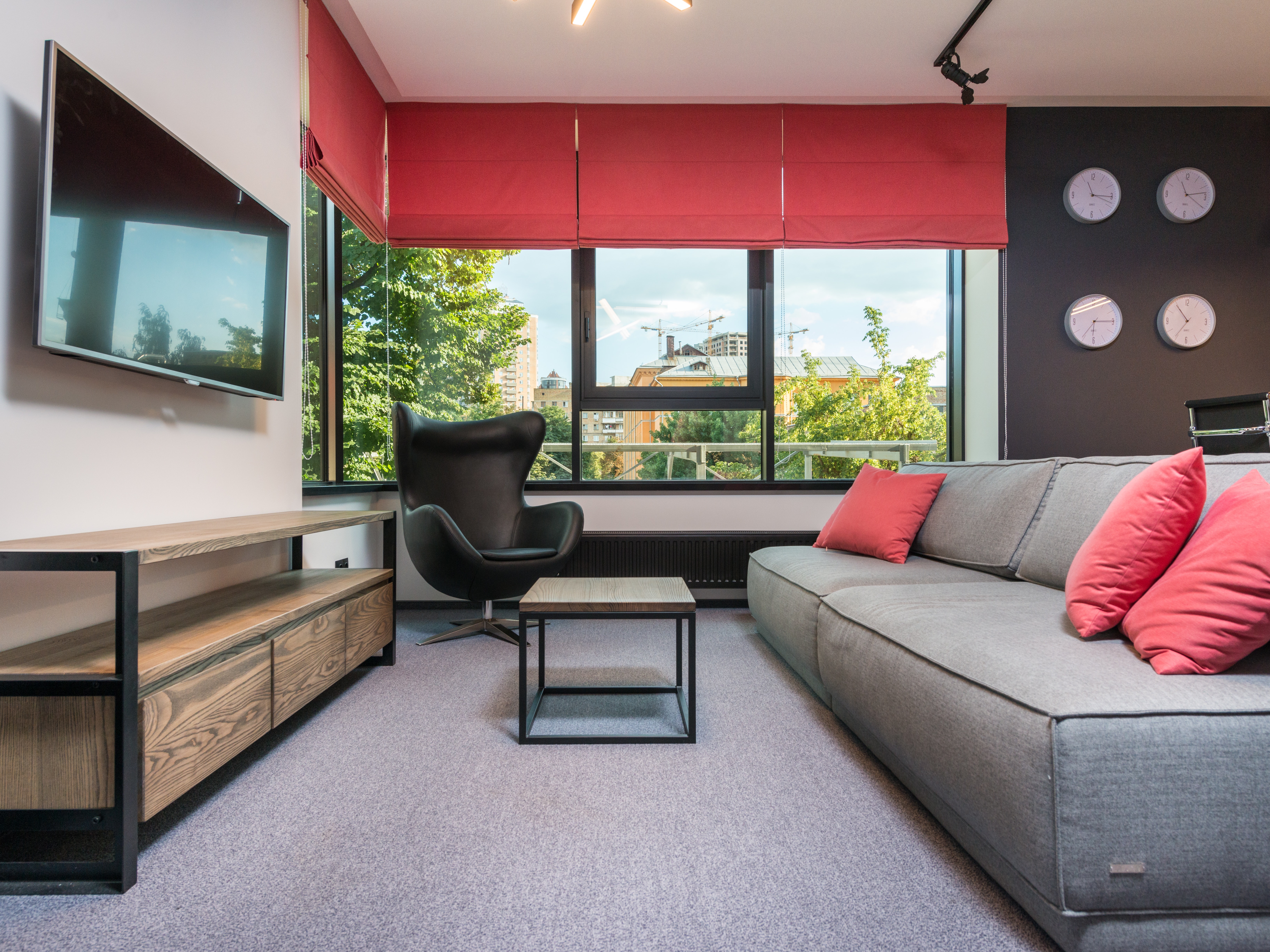 Obývačka v chladných farbách s červenými závesmi a vankúšmi
